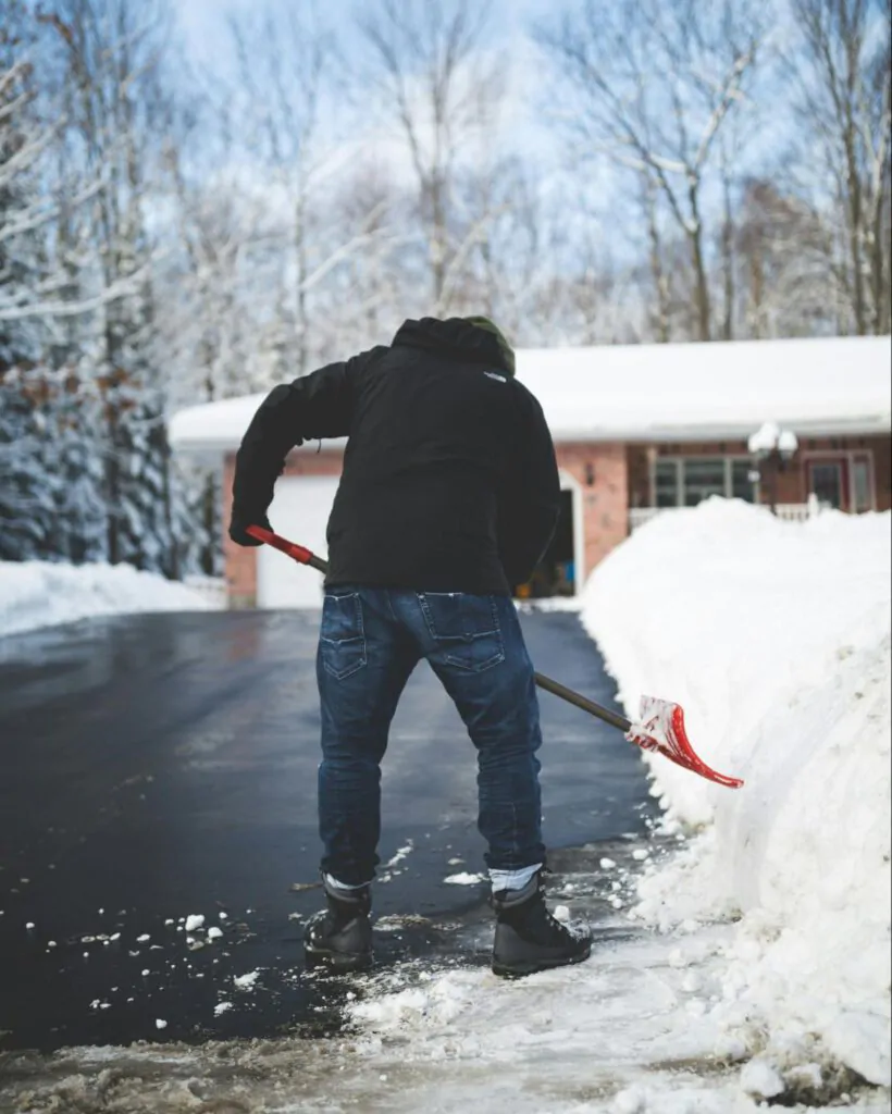 man shoveling snow off his seal coated driveway