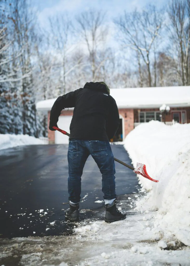 man shoveling snow off the blacktop asphalt driveway