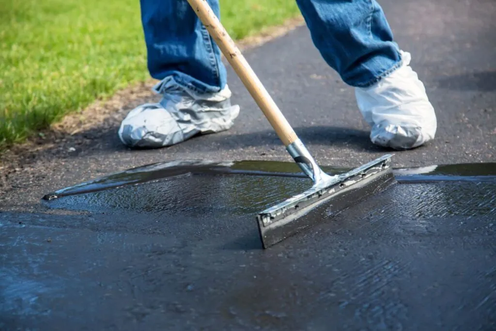 close-up contractor working on driveway sealcoating