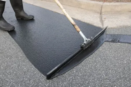 a man sealing asphalt driveway